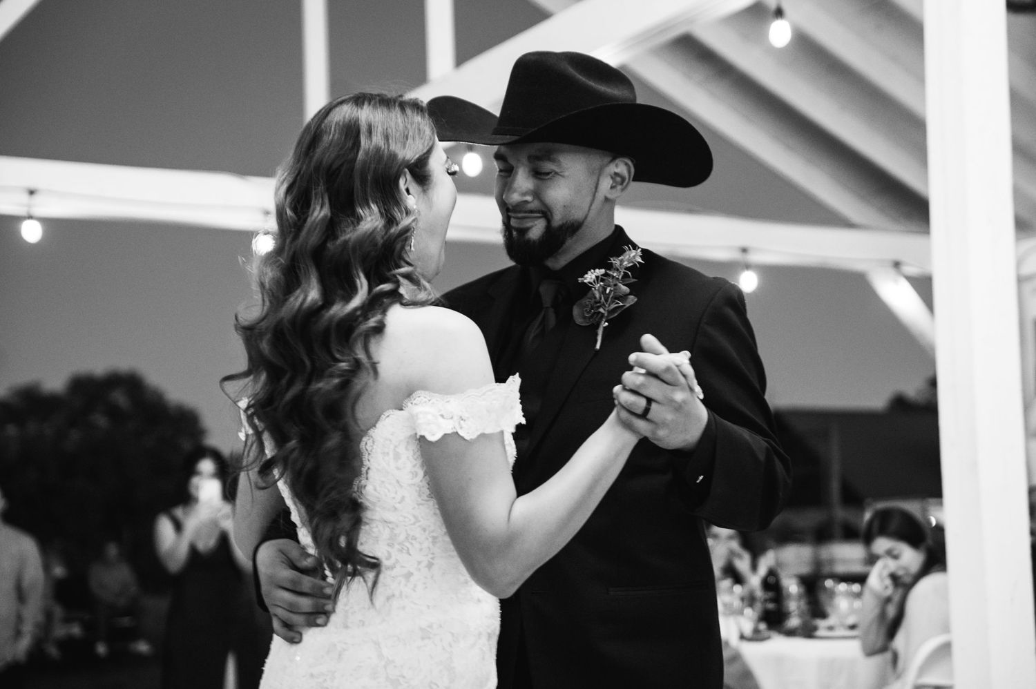 Wedding couple in western attire dancing together under covered outdoor venue.