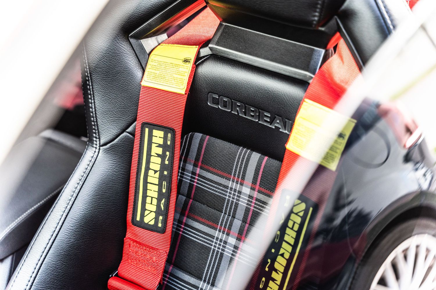 Close-up of racing harness seat belts with red straps in modified car interior.