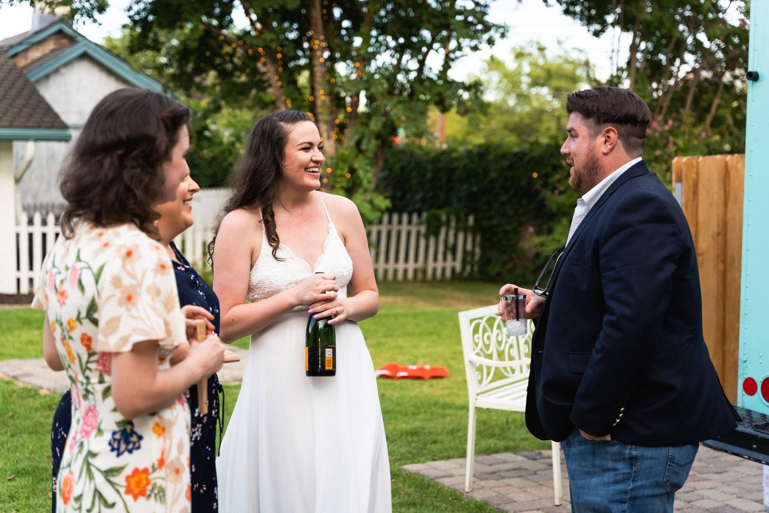 Three people chatting and laughing at an outdoor garden party.