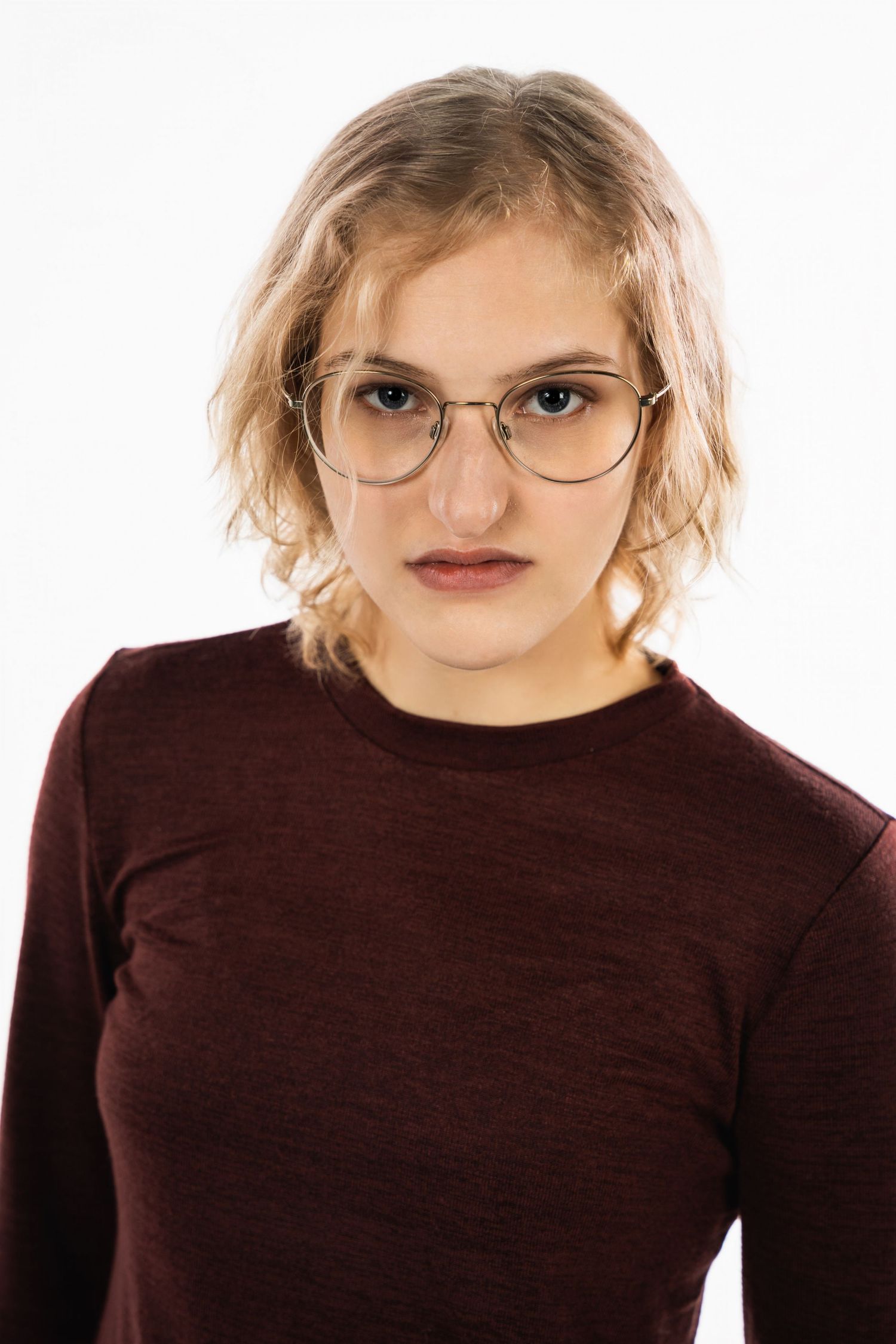 Studio portrait of someone wearing glasses and burgundy sweater against white background.