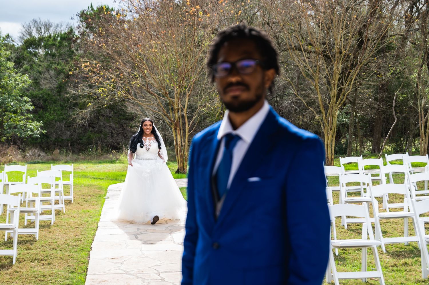 A wedding ceremony setup outdoors with white chairs and a stone aisle.