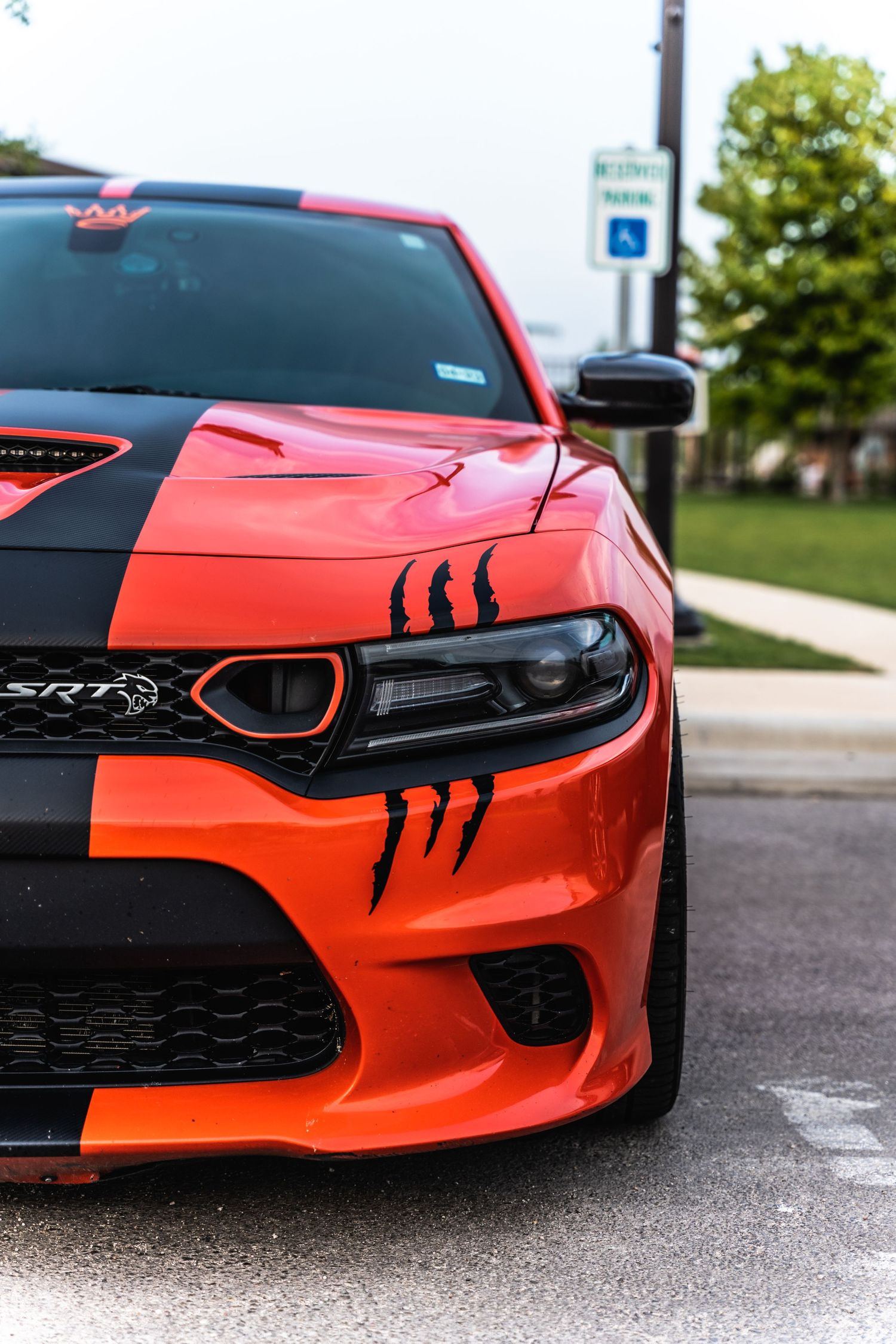 Close-up view of an orange and black Dodge Charger SRT front end with aggressive claw mark decals.