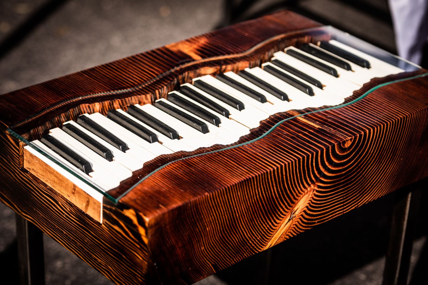 Piano keyboard embedded in rustic wooden surface with detailed grain patterns.