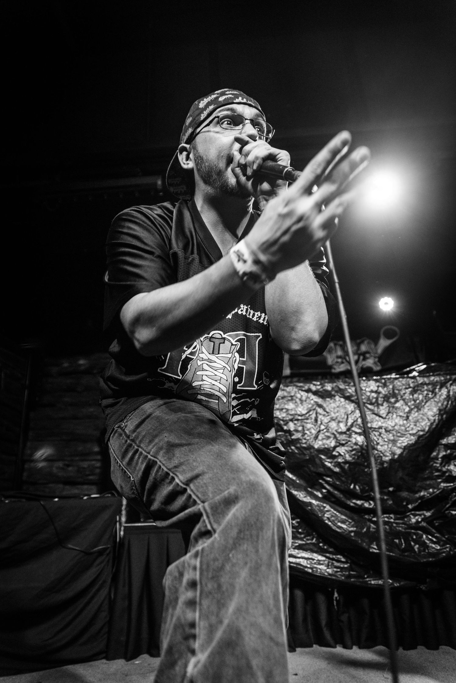 Concert performer in black shirt gestures while singing onstage.