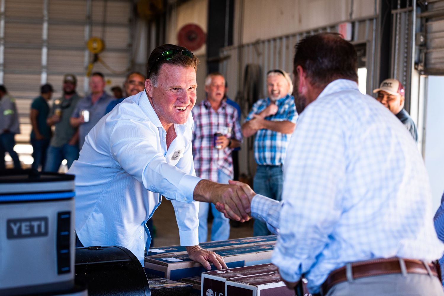Business handshake between two professionals at corporate event with YETI cooler visible.