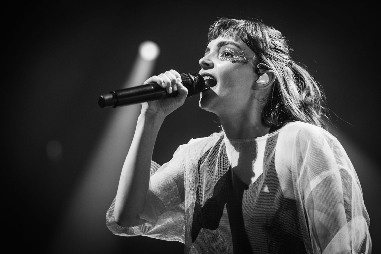 Dramatic black and white close-up of performer singing emotionally into microphone.