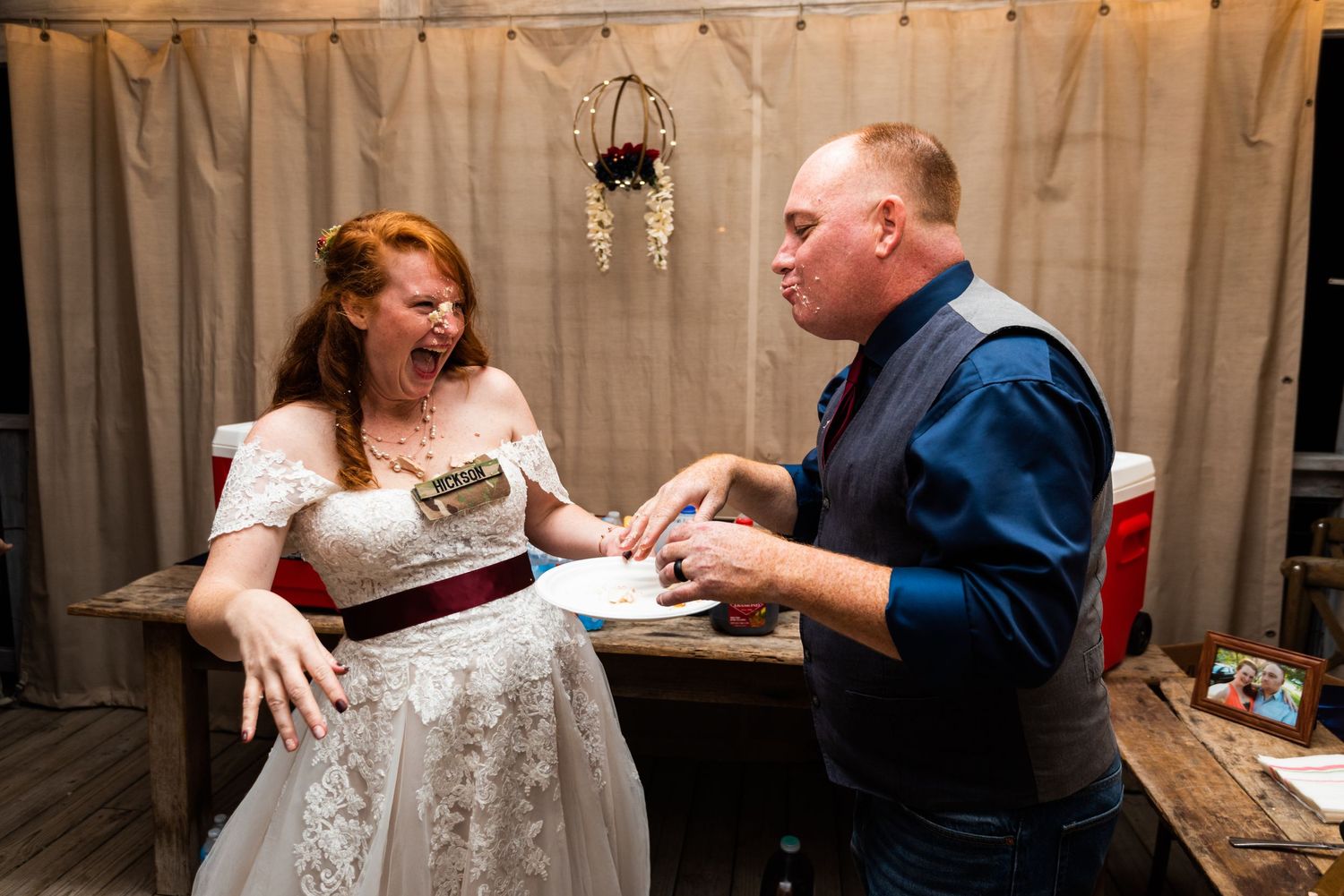A joyful moment of wedding cake sharing between two people at a reception.