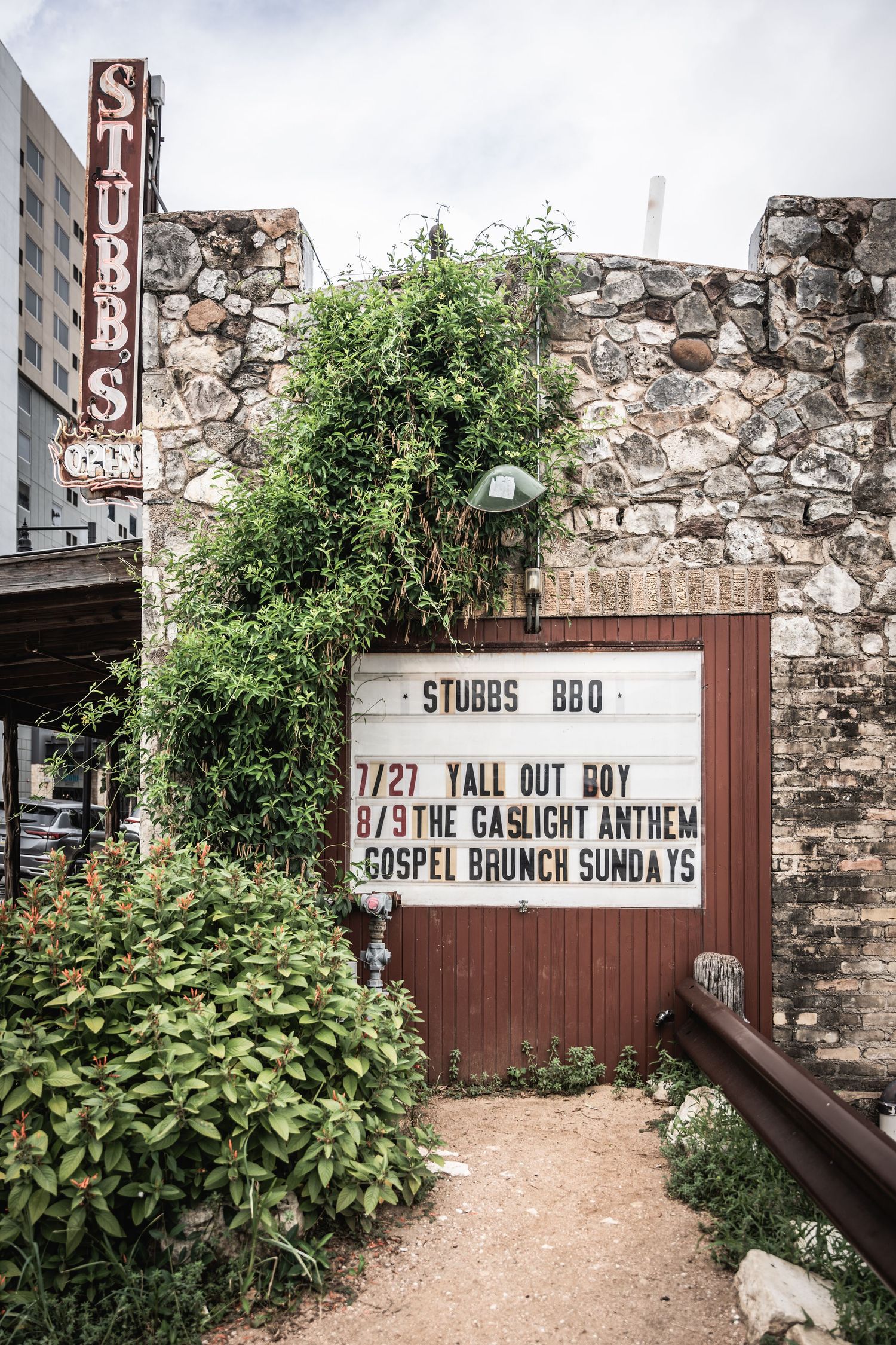 Vintage stone wall with Stubb's BBQ sign showing concert listings and upcoming events at the music venue.