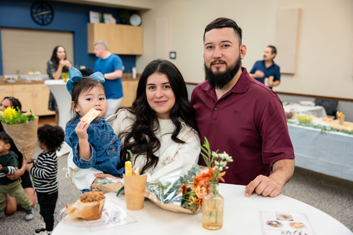 Guests enjoying refreshments at a party with food and drinks displayed on tables.