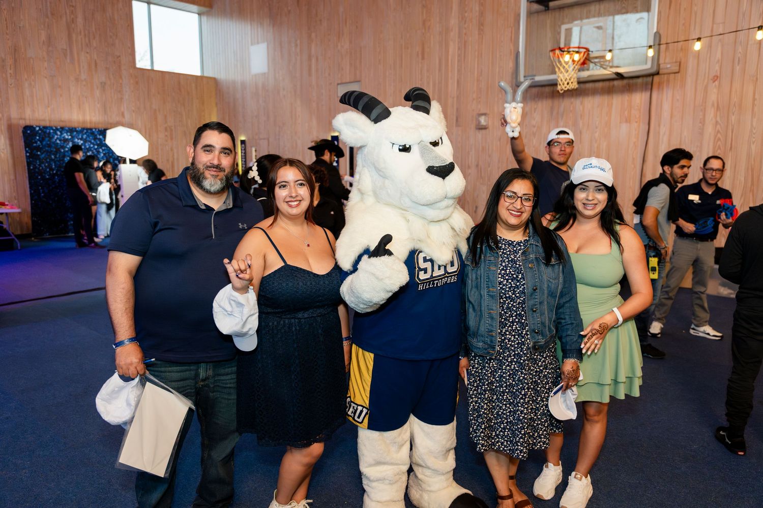 Group of people posing with a large white polar bear mascot at an indoor event space.