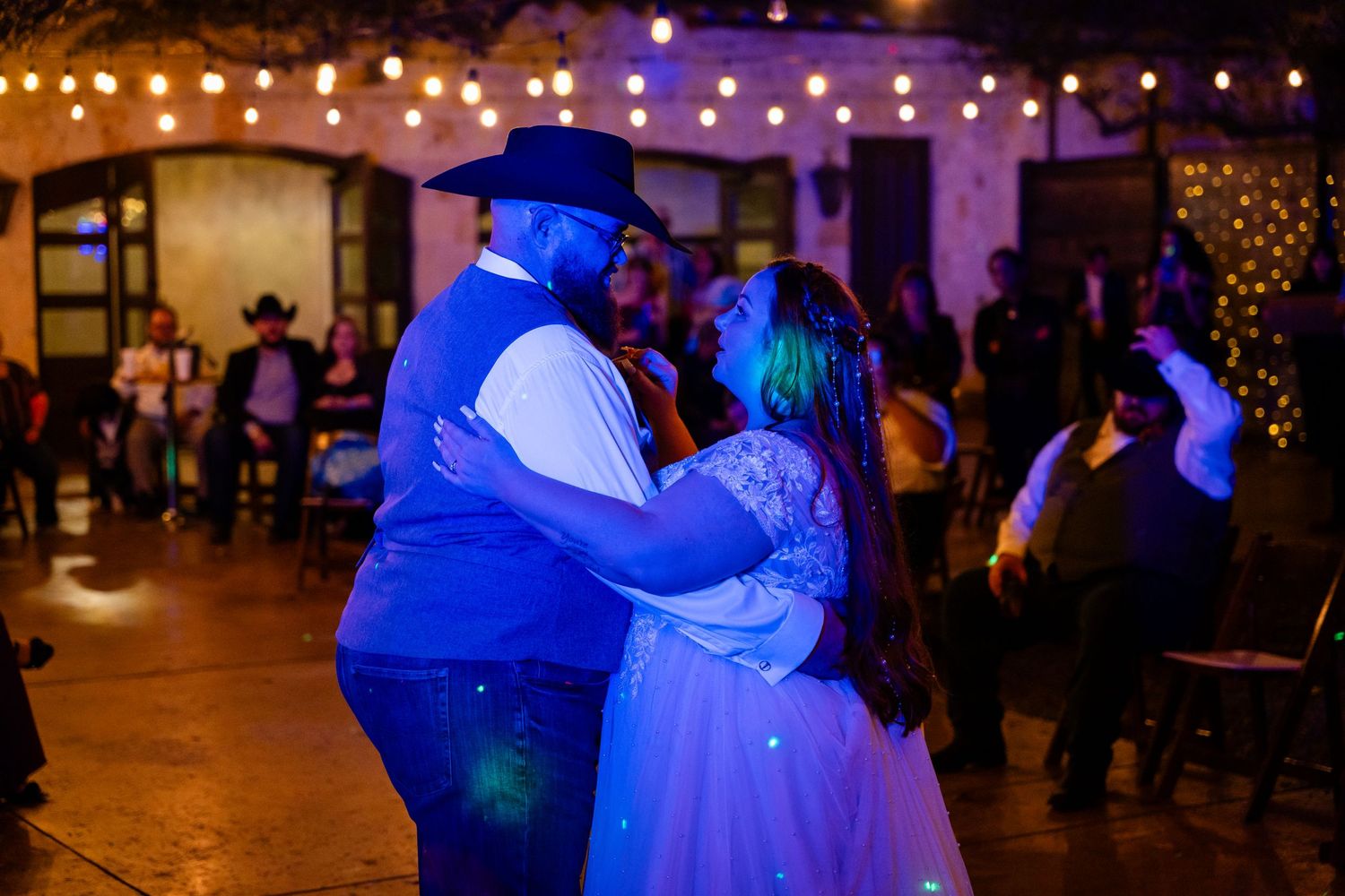 Couple sharing a dance under blue and purple lighting at indoor reception venue.