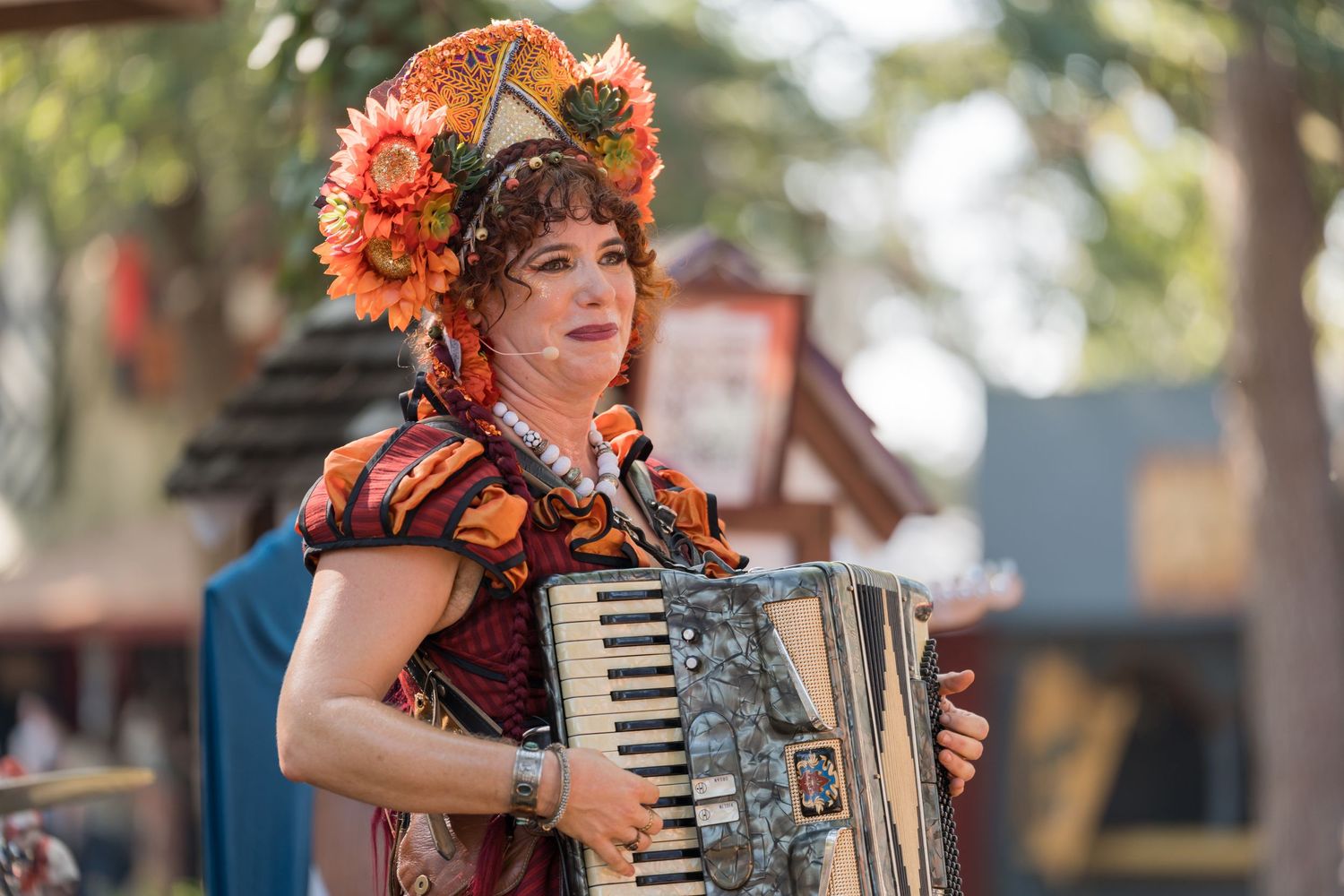 Musical performer in a colorful costume playing accordion at a renaissance festival.