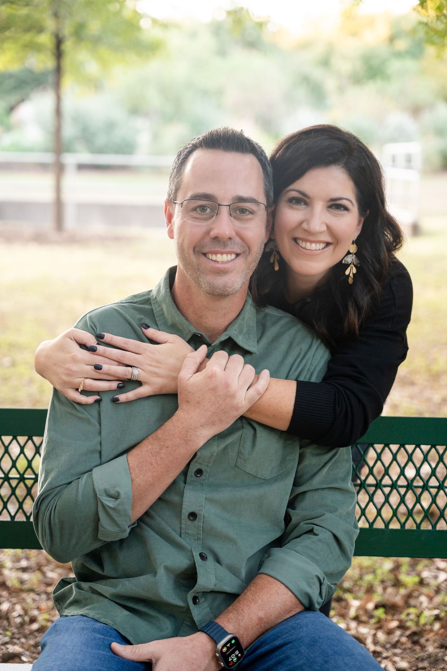 A loving couple shares an embrace while sitting on a park bench during golden hour.