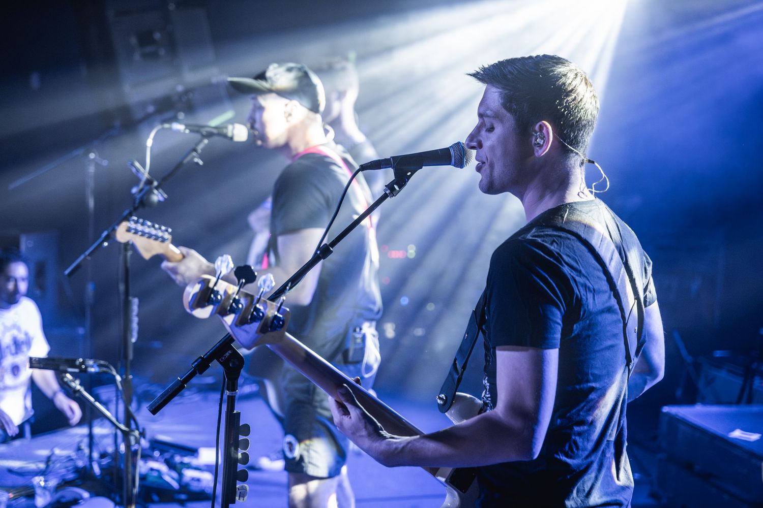Musician playing guitar on stage with dramatic backlighting and smoke effects.