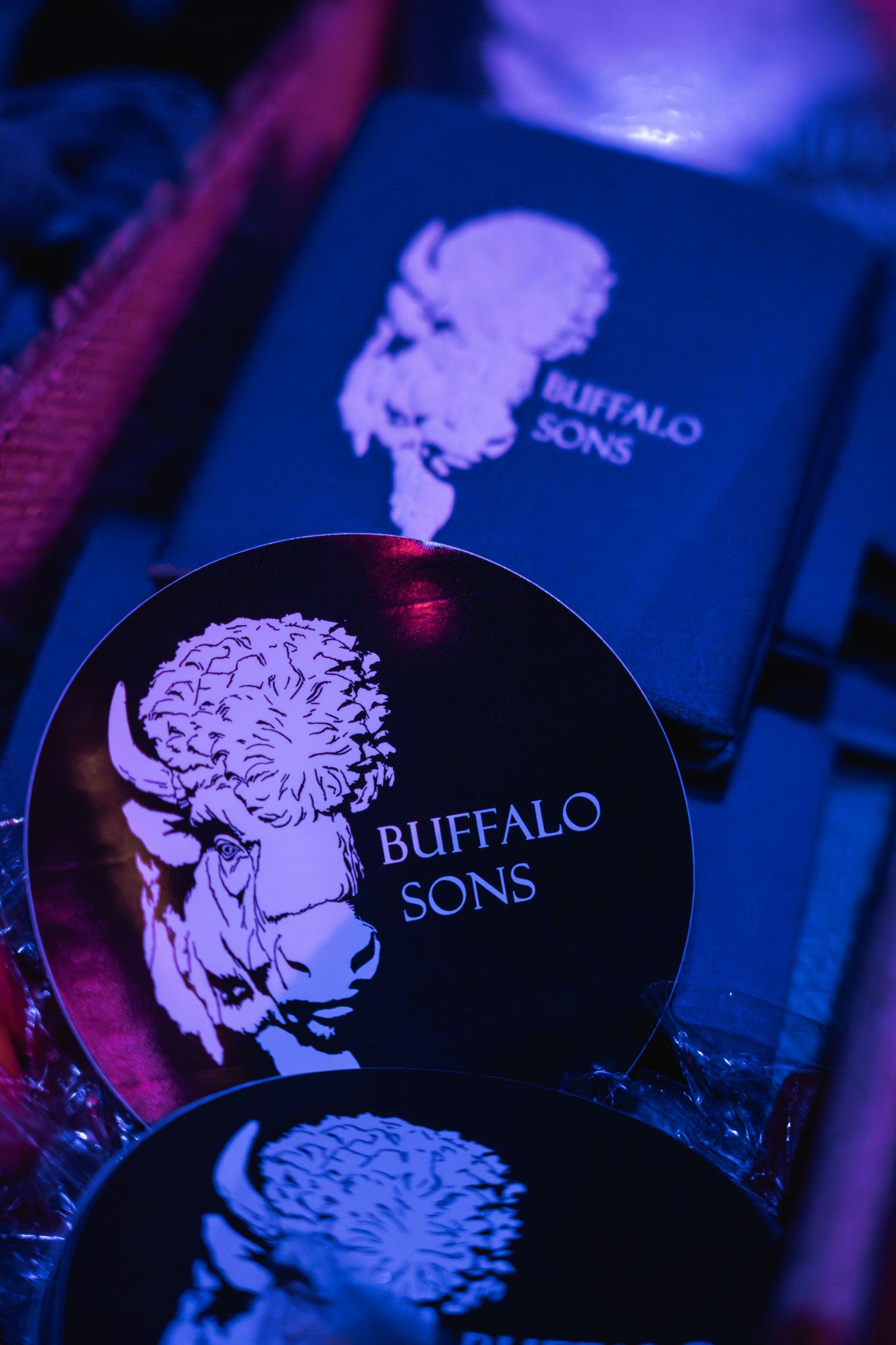 Close-up of Buffalo Sons branded merchandise with buffalo logo in purple lighting.