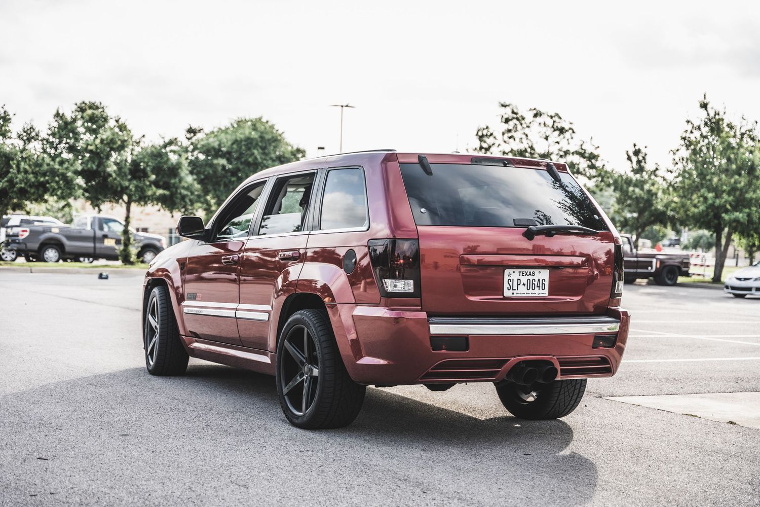 Red Jeep Grand Cherokee SRT8 with black wheels viewed from rear quarter.