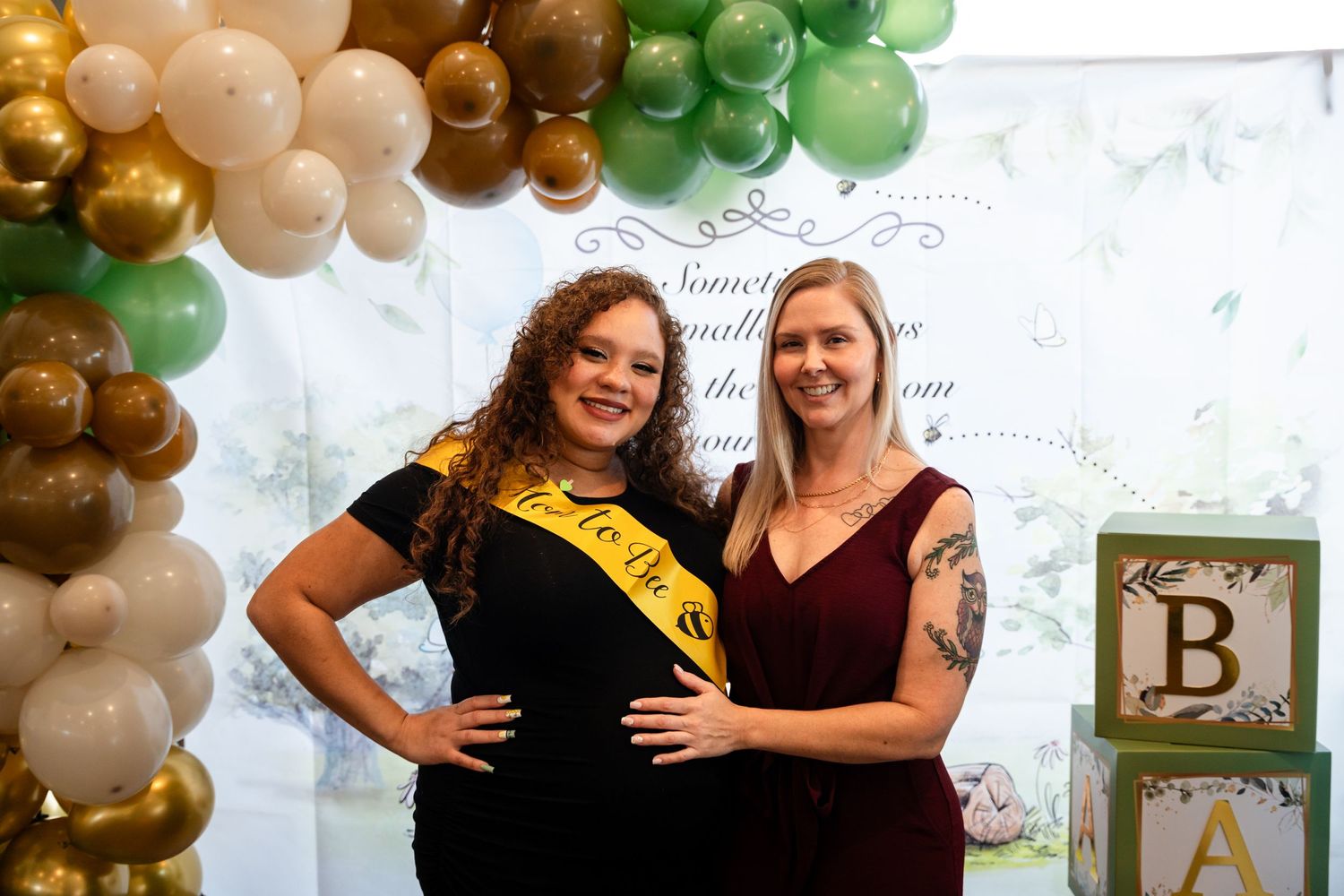 Two guests celebrating at a party with decorative balloons and a photo backdrop.