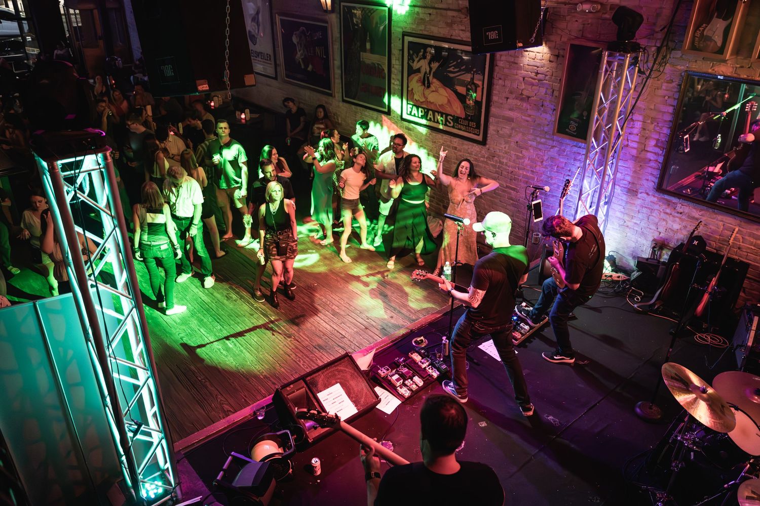 Overhead view of crowded dance floor with green stage lighting and band performing live music.