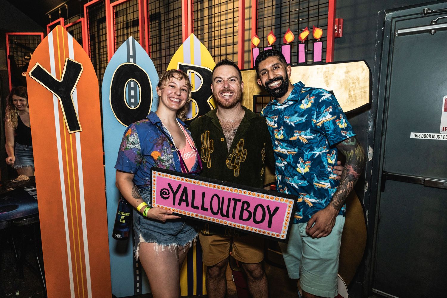 Decorative surfboard wall display with YallOutBoy signage at music venue.