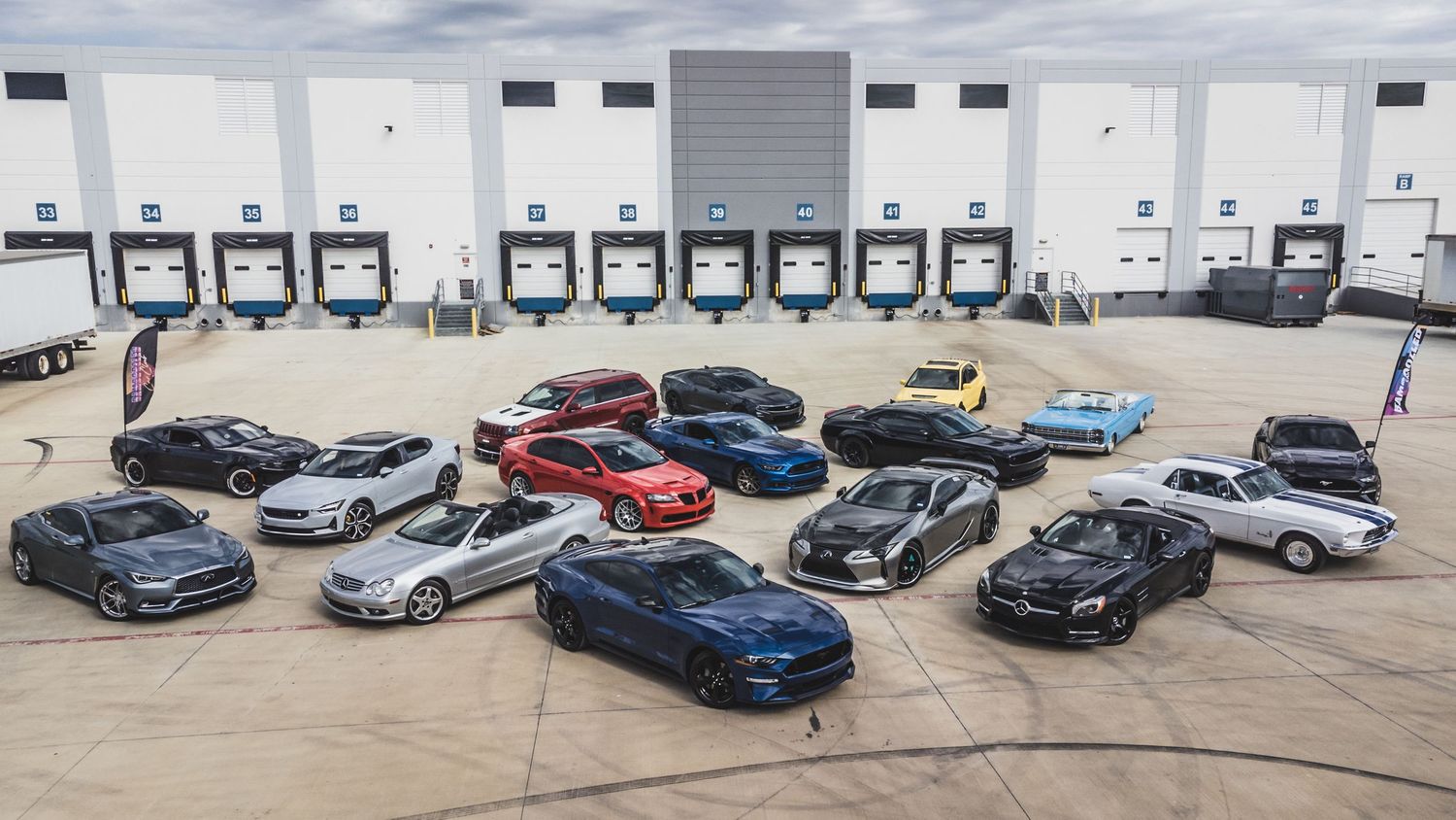 Sports cars and performance vehicles lined up for a group photo at a distribution center.
