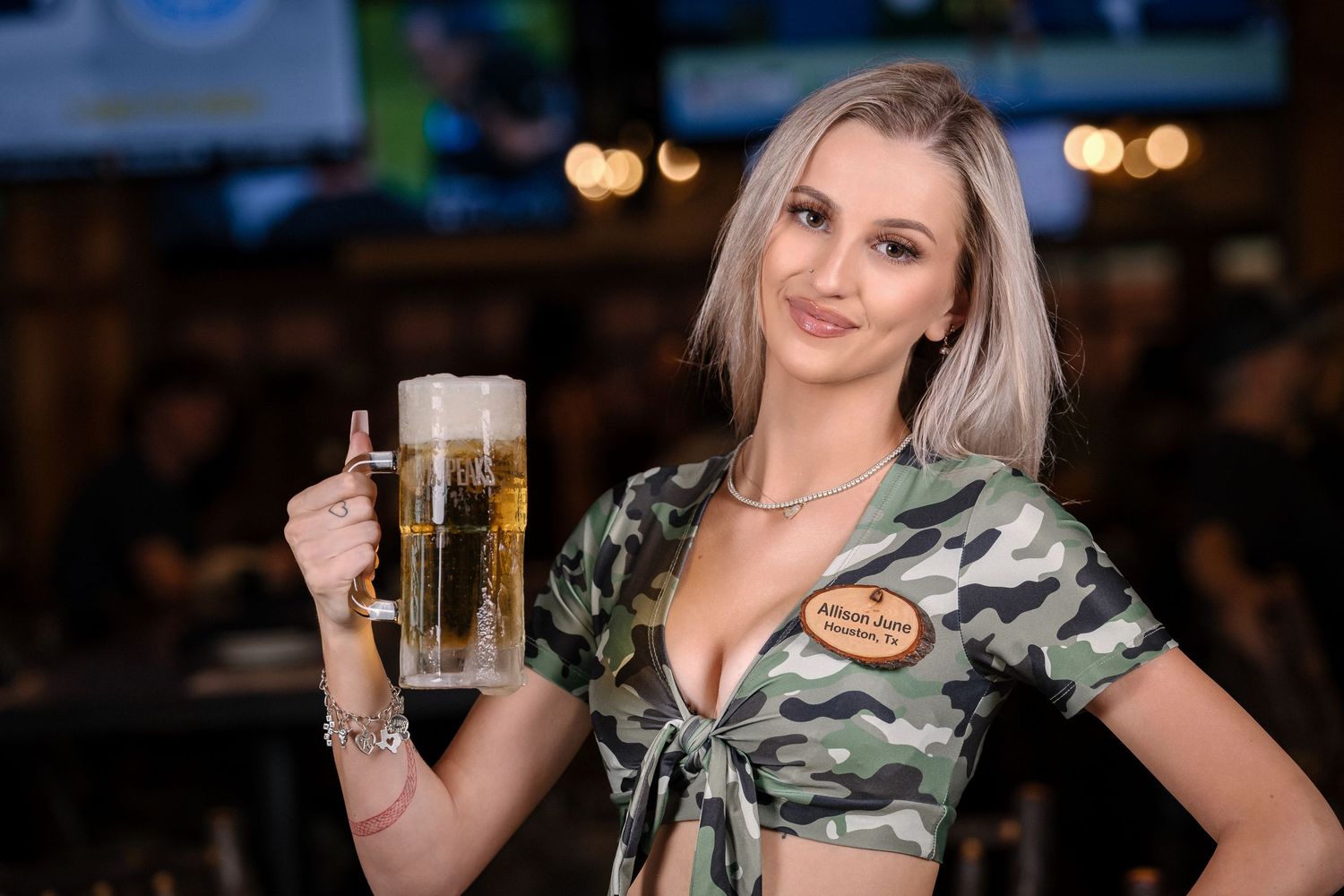 Bar server displaying draft beer while wearing military-inspired uniform top.