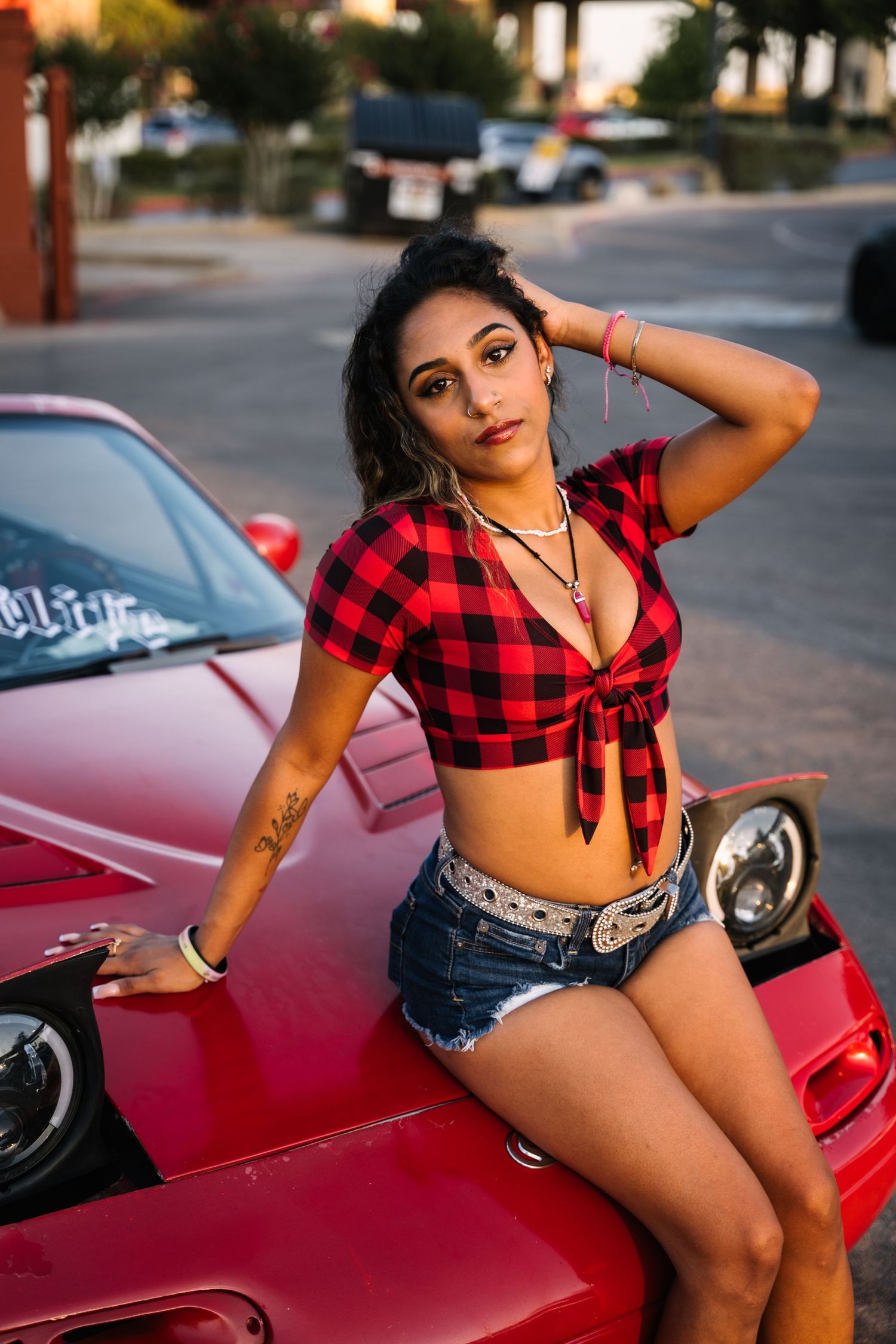 Car meet gathering at sunset with customized vehicles in a parking lot.