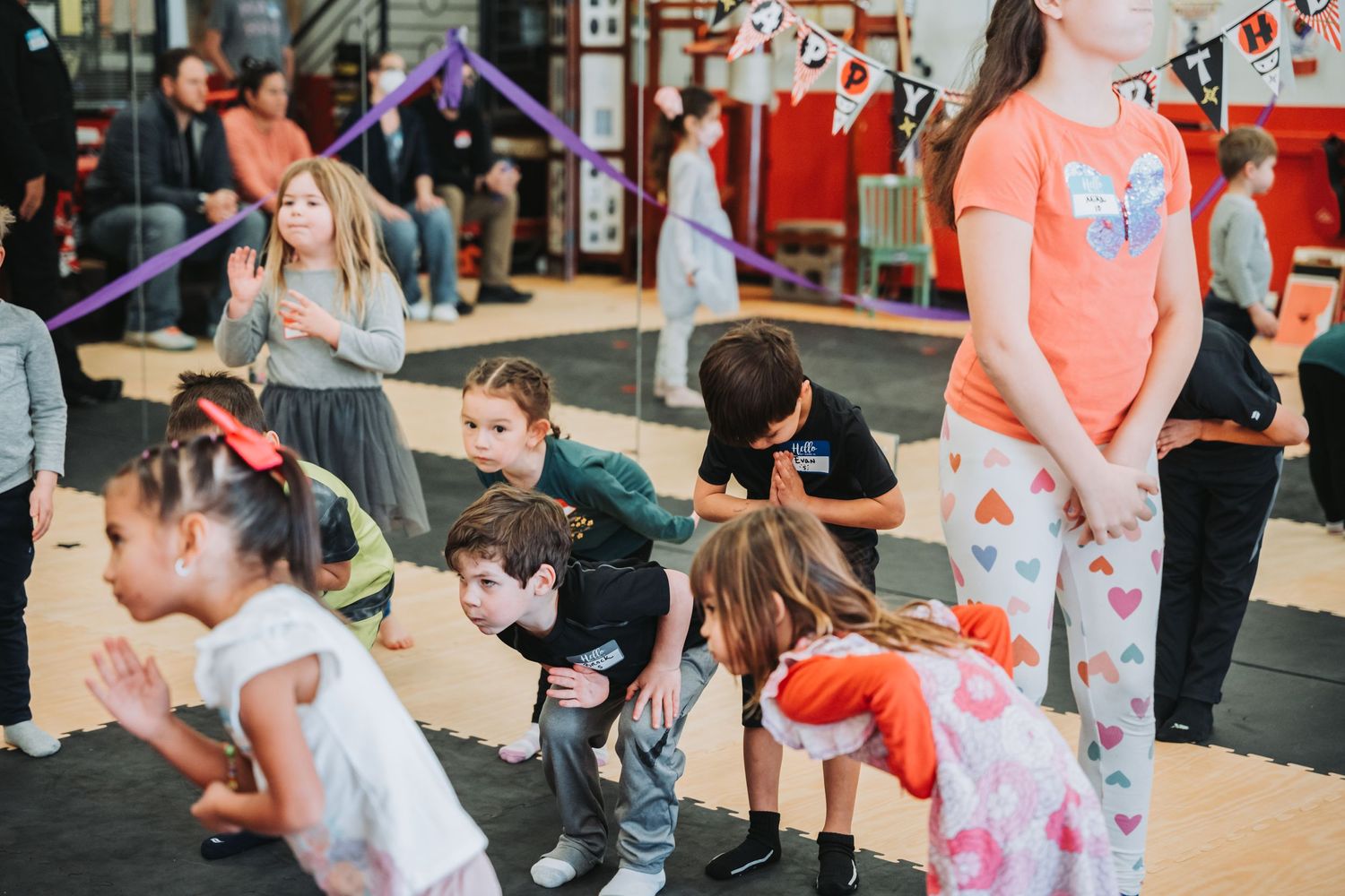 Children participating in an energetic group exercise class with colorful training equipment.