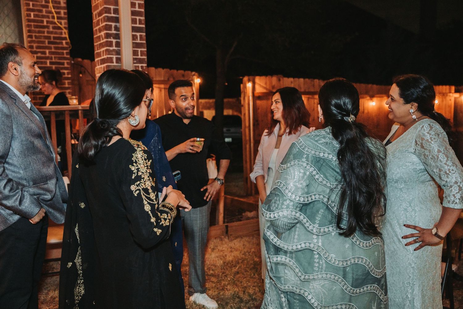 Group of people having an animated conversation at an outdoor evening gathering.