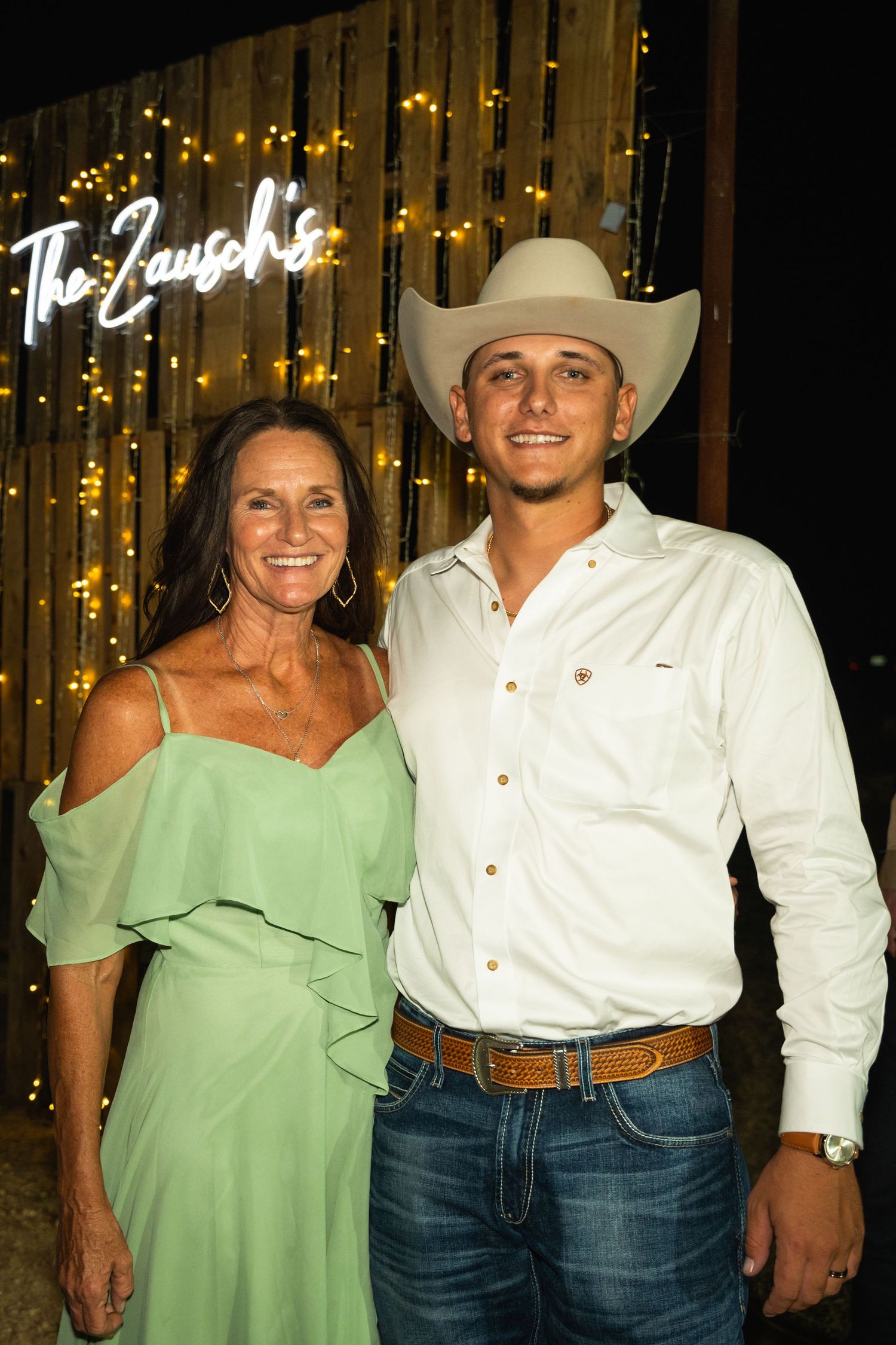 Western-styled evening portrait in front of illuminated signage and fairy lights.