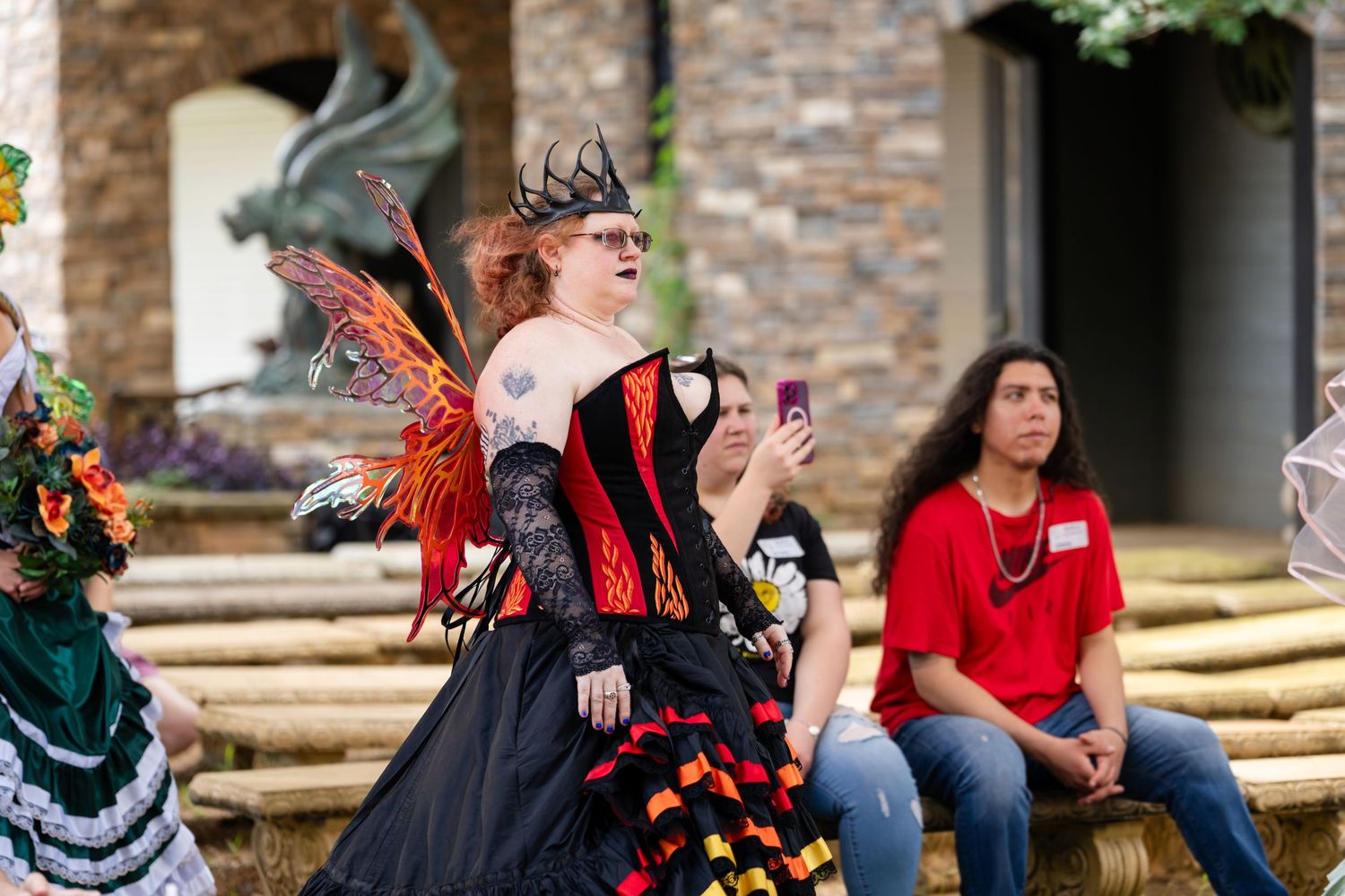 Person in fairy queen costume with wings and crown at a Renaissance festival outdoor event.