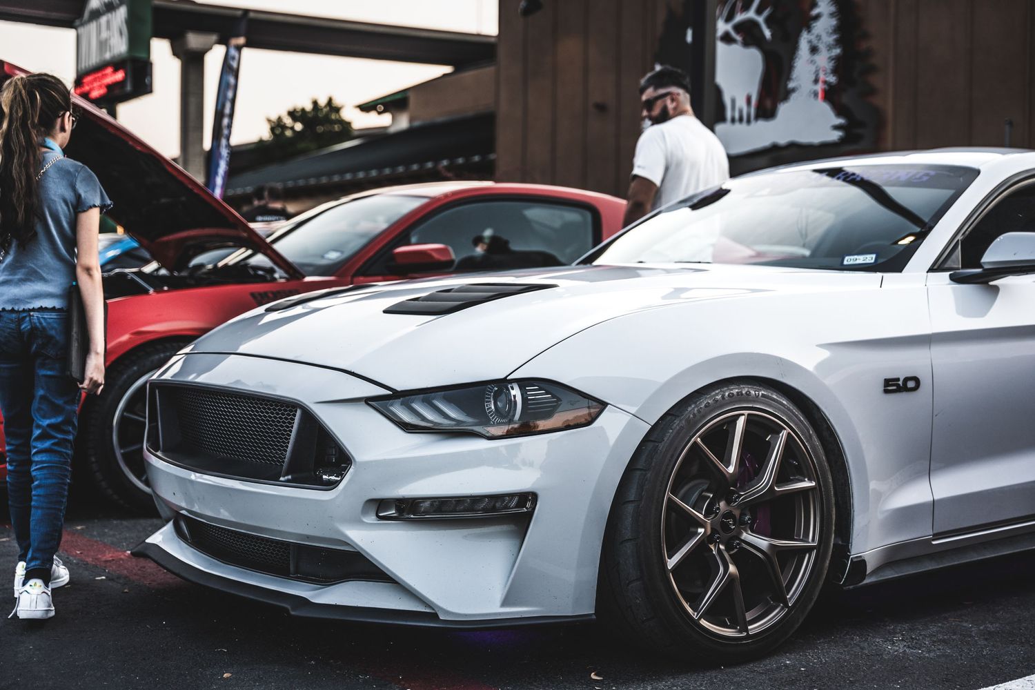 Silver Ford Mustang GT showcasing custom wheels and body modifications at car show.