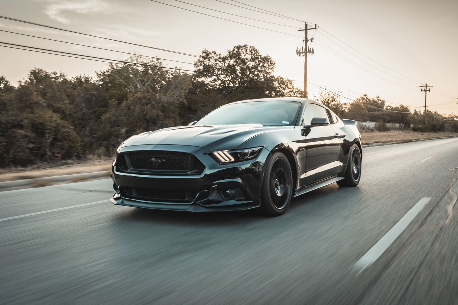 Custom Ford Mustang with aggressive styling photographed in motion on a suburban street.