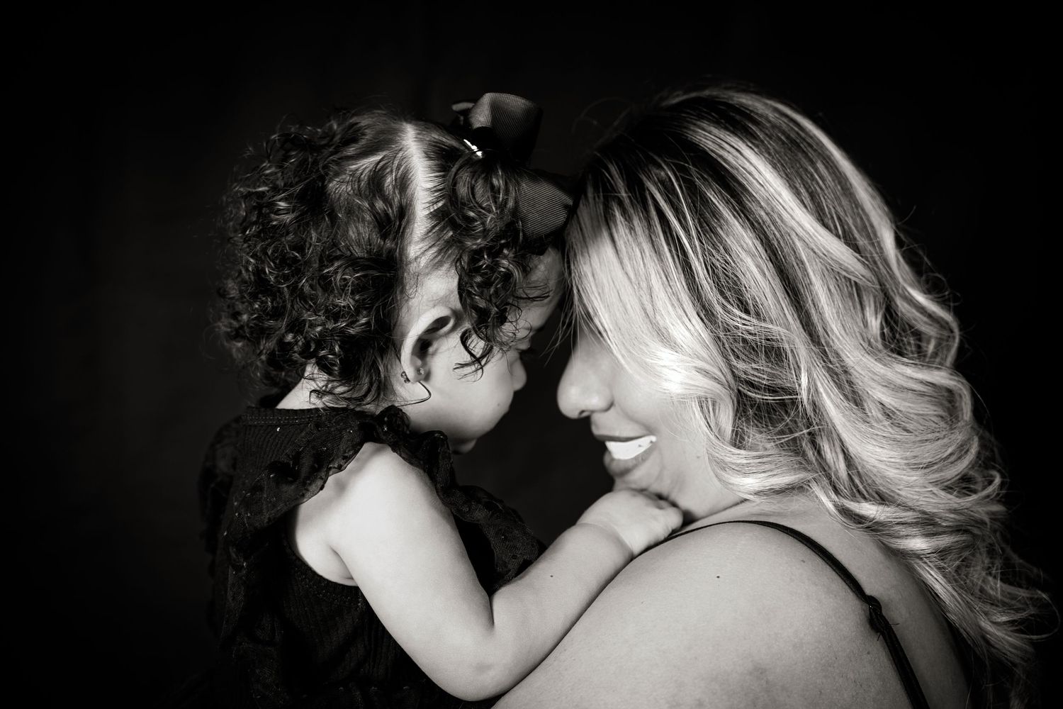 Tender black and white portrait showing parent and child in loving embrace.