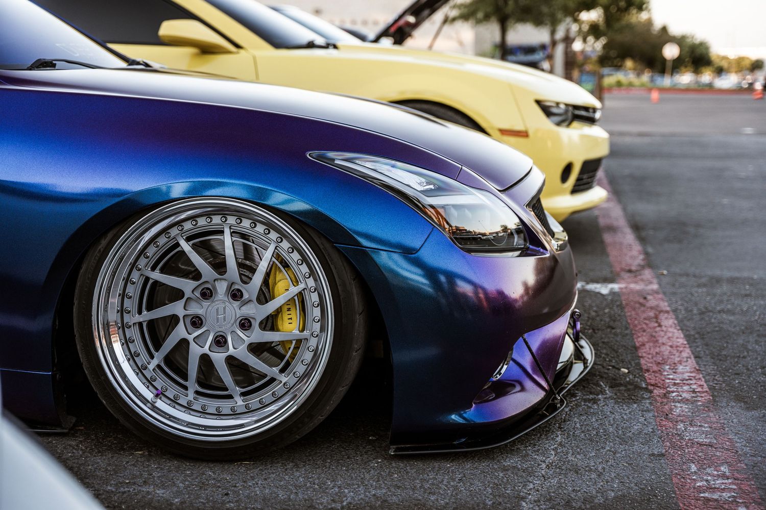 Close-up of a modified blue sports car with custom chrome wheels and lowered suspension.