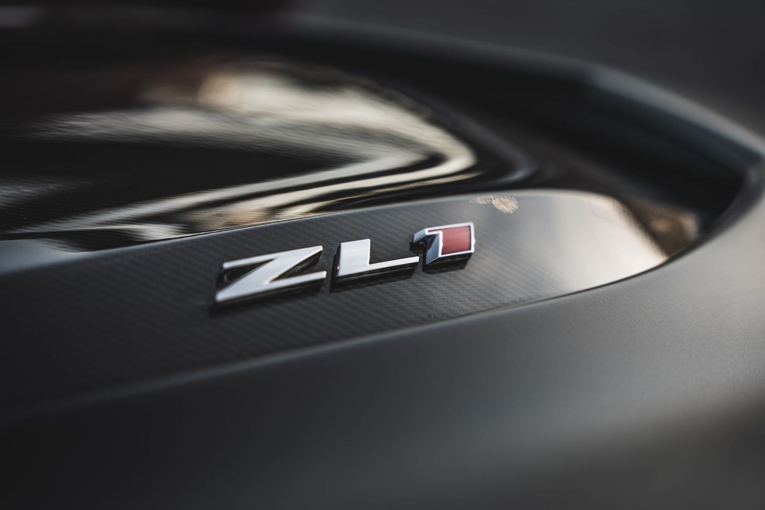 Close-up of ZL1 badge on black car surface.