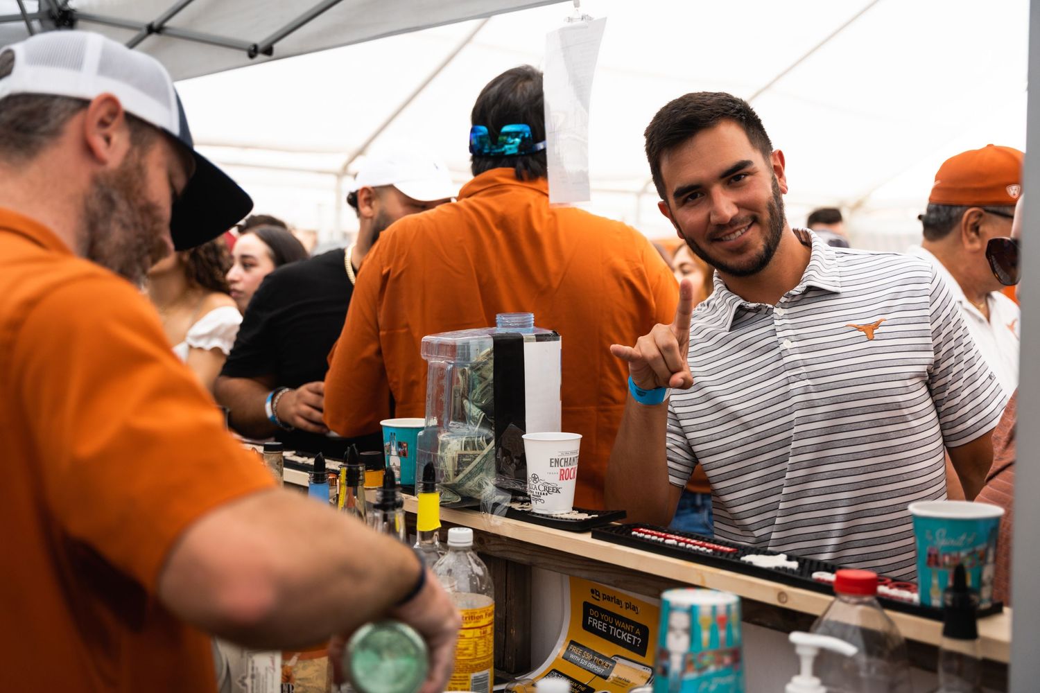 People gather at an outdoor beverage tent serving refreshments at a casual event.