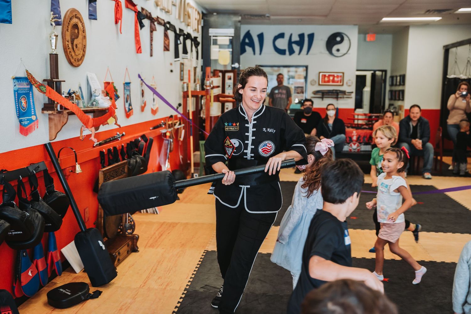 Students gather around their instructor during a martial arts lesson in a decorated training studio.