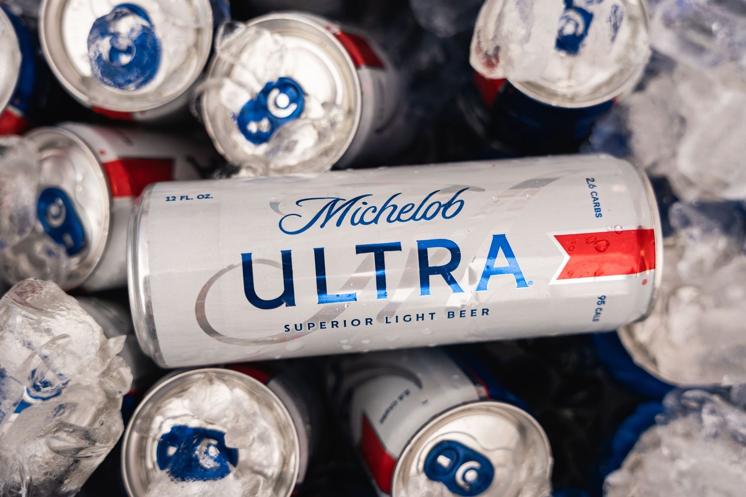 Cold cans of Michelob Ultra beer on ice with blue and red branding visible.