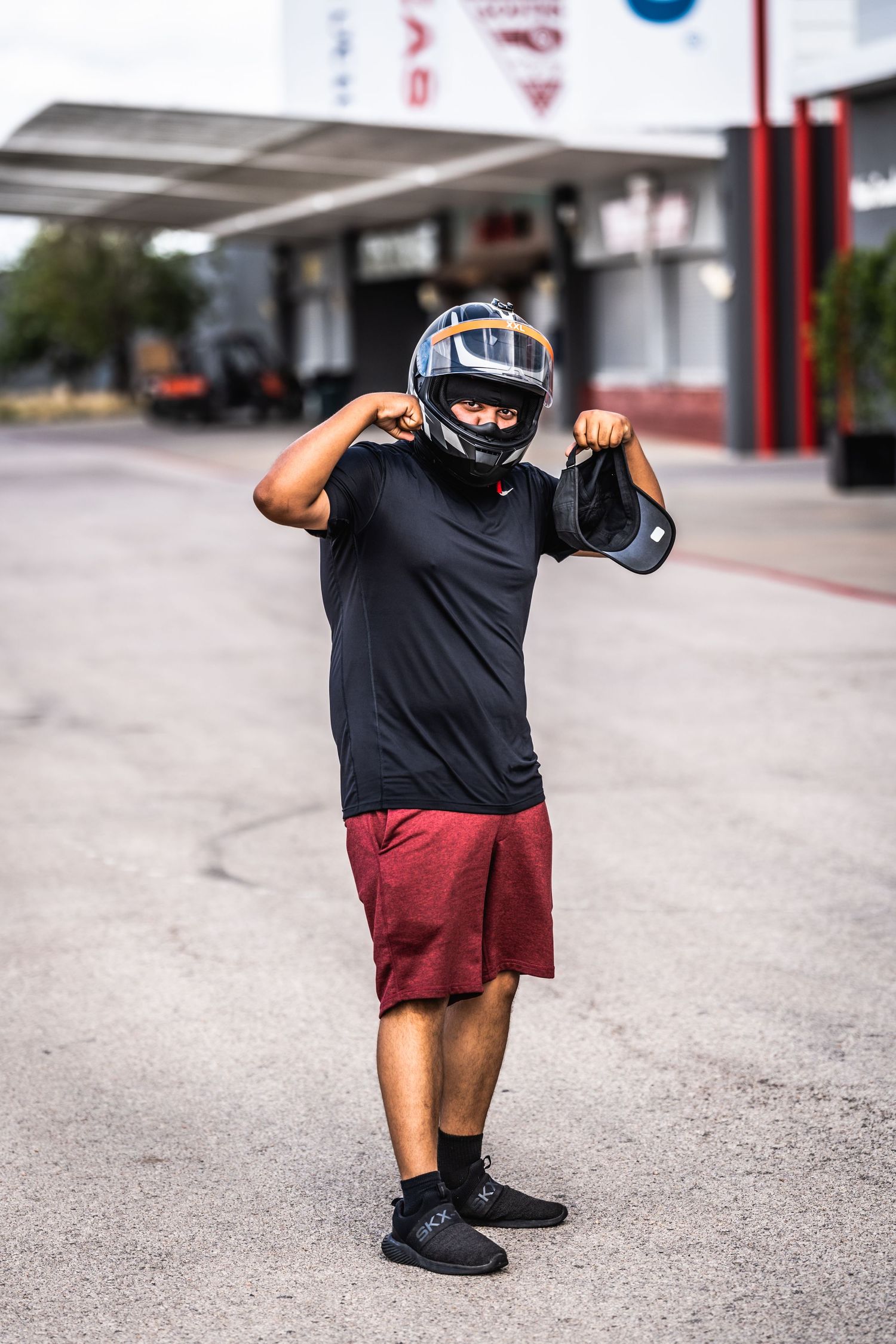 Person in racing gear and helmet posing outside Circuit of the Americas facility.