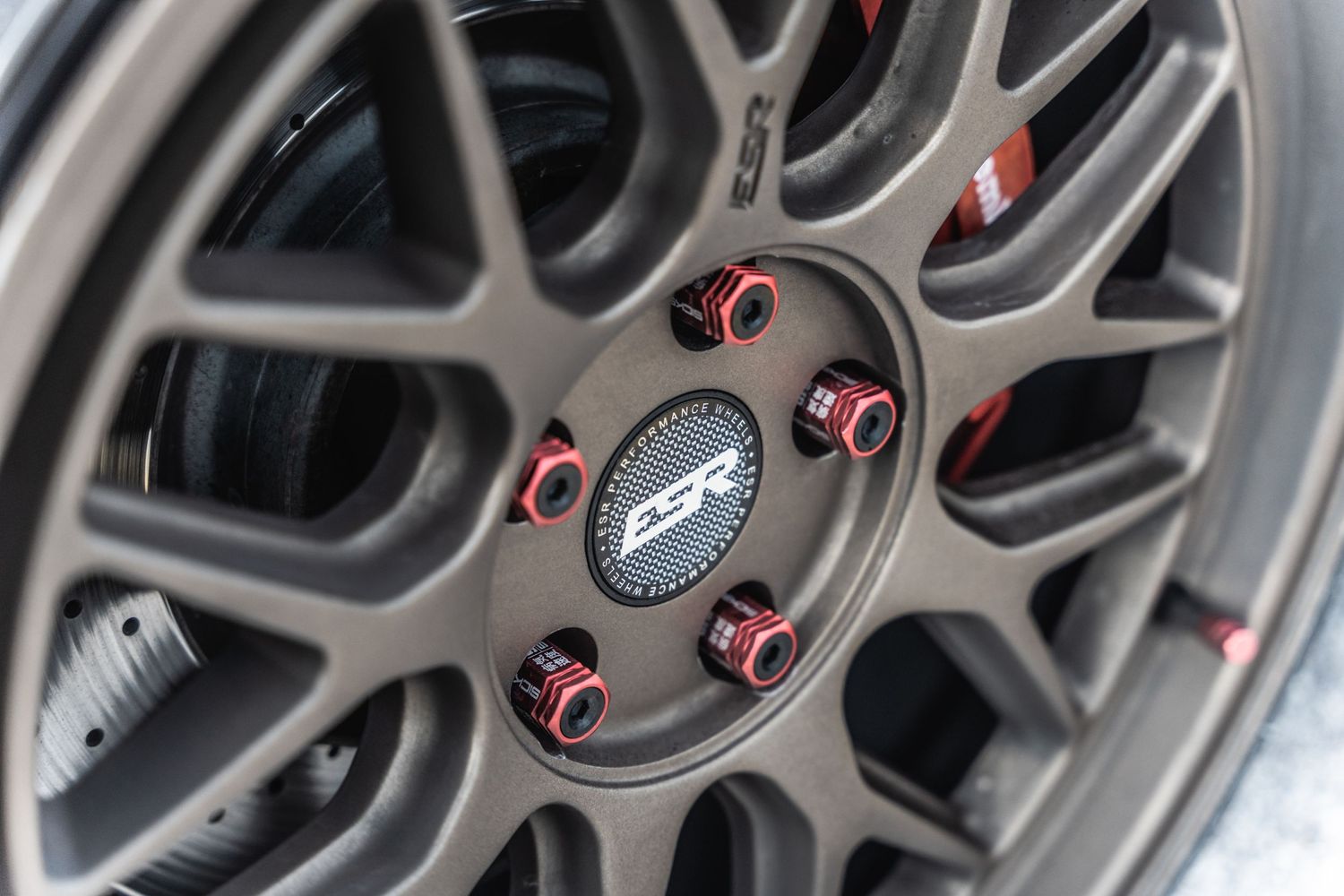 Detailed view of a lightweight performance wheel hub with red anodized lug nuts.