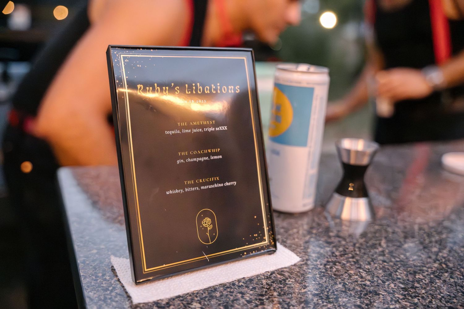 A menu card displayed on a dark granite countertop with bar accessories.