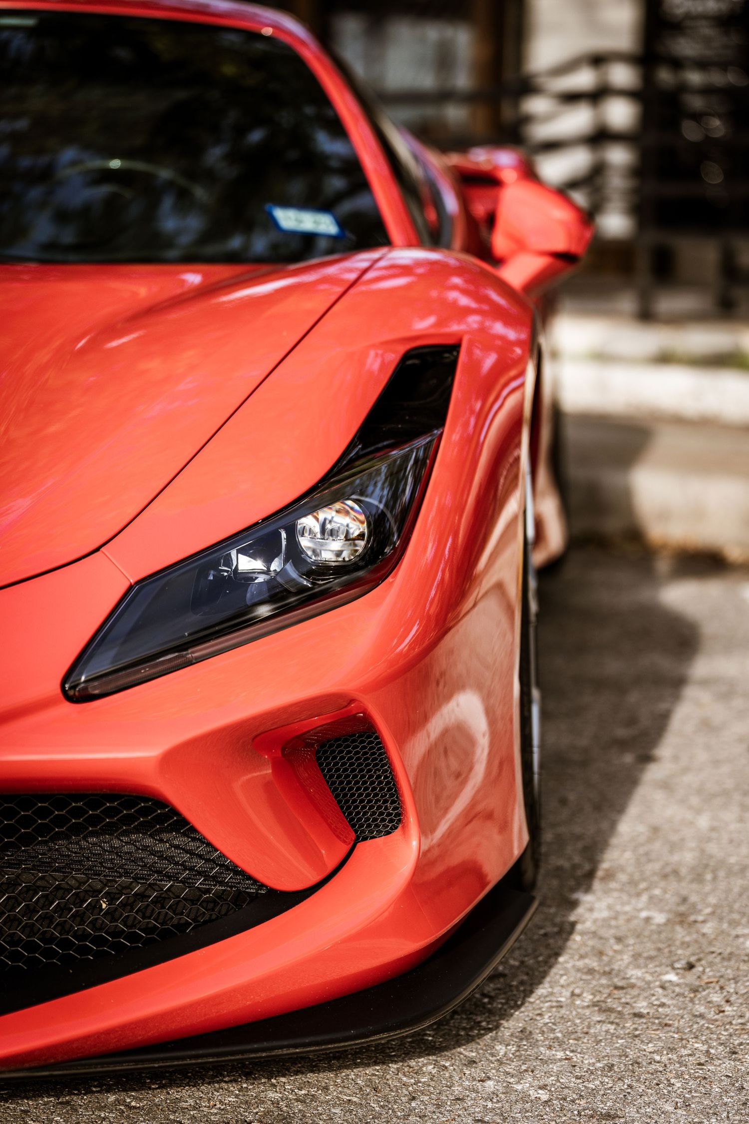 Close-up of a red Ferrari sports car's aggressive front headlight and bumper design.