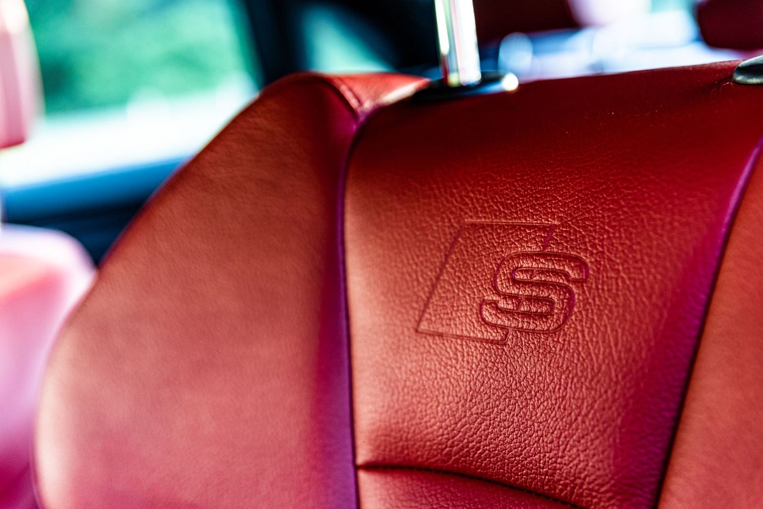 Detail shot of red leather Audi S-line seat with embossed logo.