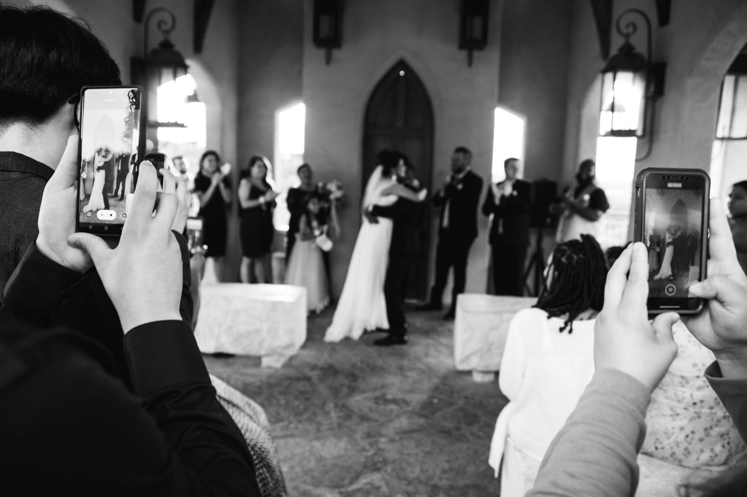 Wedding guests capture photos of the ceremony in a beautiful church setting.