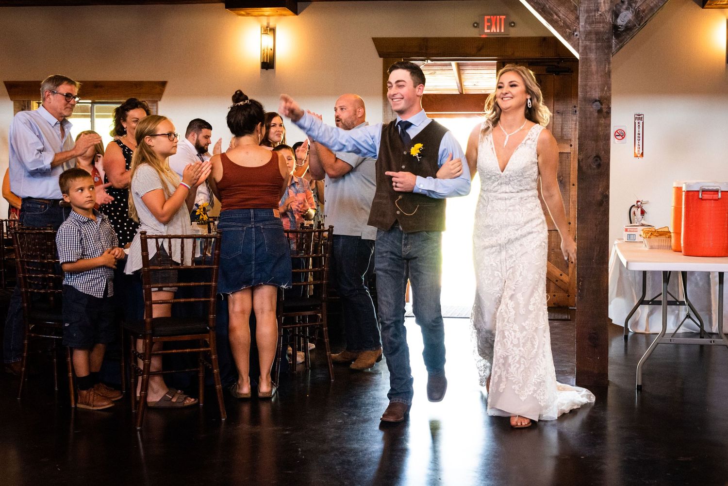 Wedding celebration entrance into rustic venue with guests cheering and applauding.