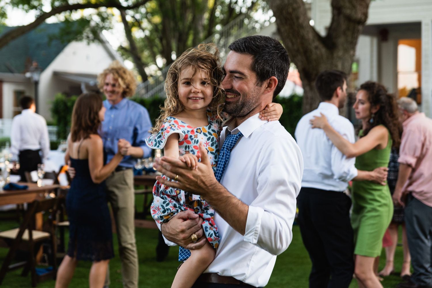 A tender moment between parent and child at an outdoor garden party.