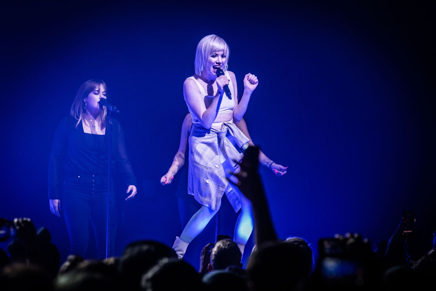 Energetic concert performance with blue stage lighting and silhouetted crowd.