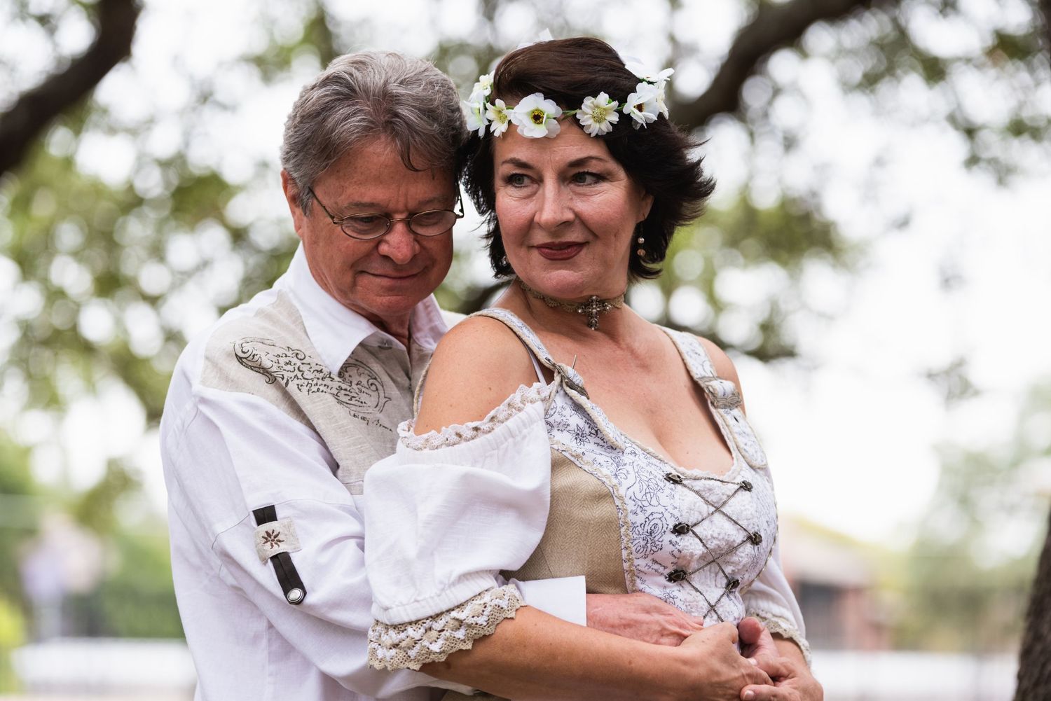 A tender moment between a couple in coordinated white and beige vintage-style outfits.