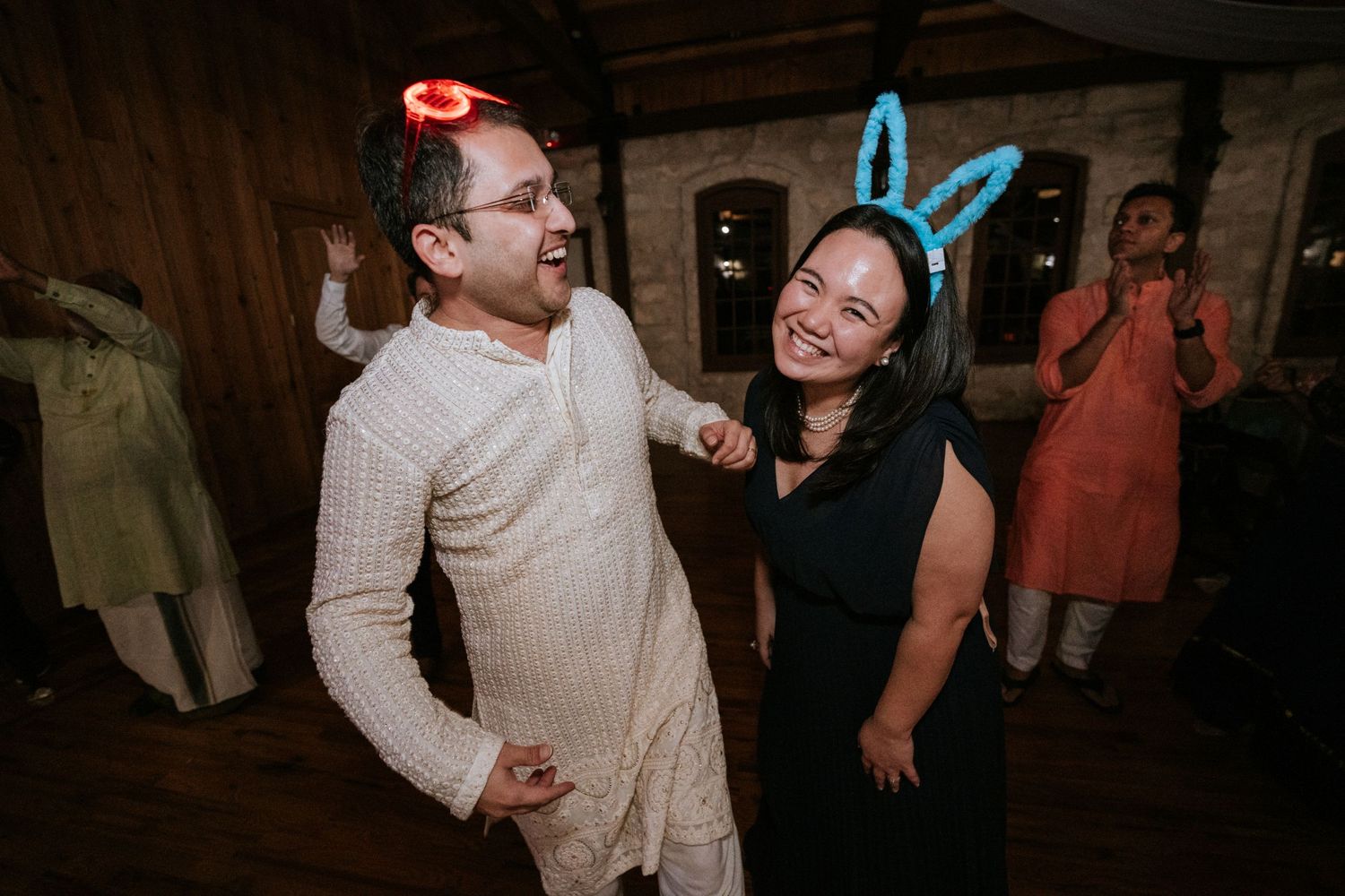 Two guests dancing playfully with glowing party accessories at a nighttime celebration.