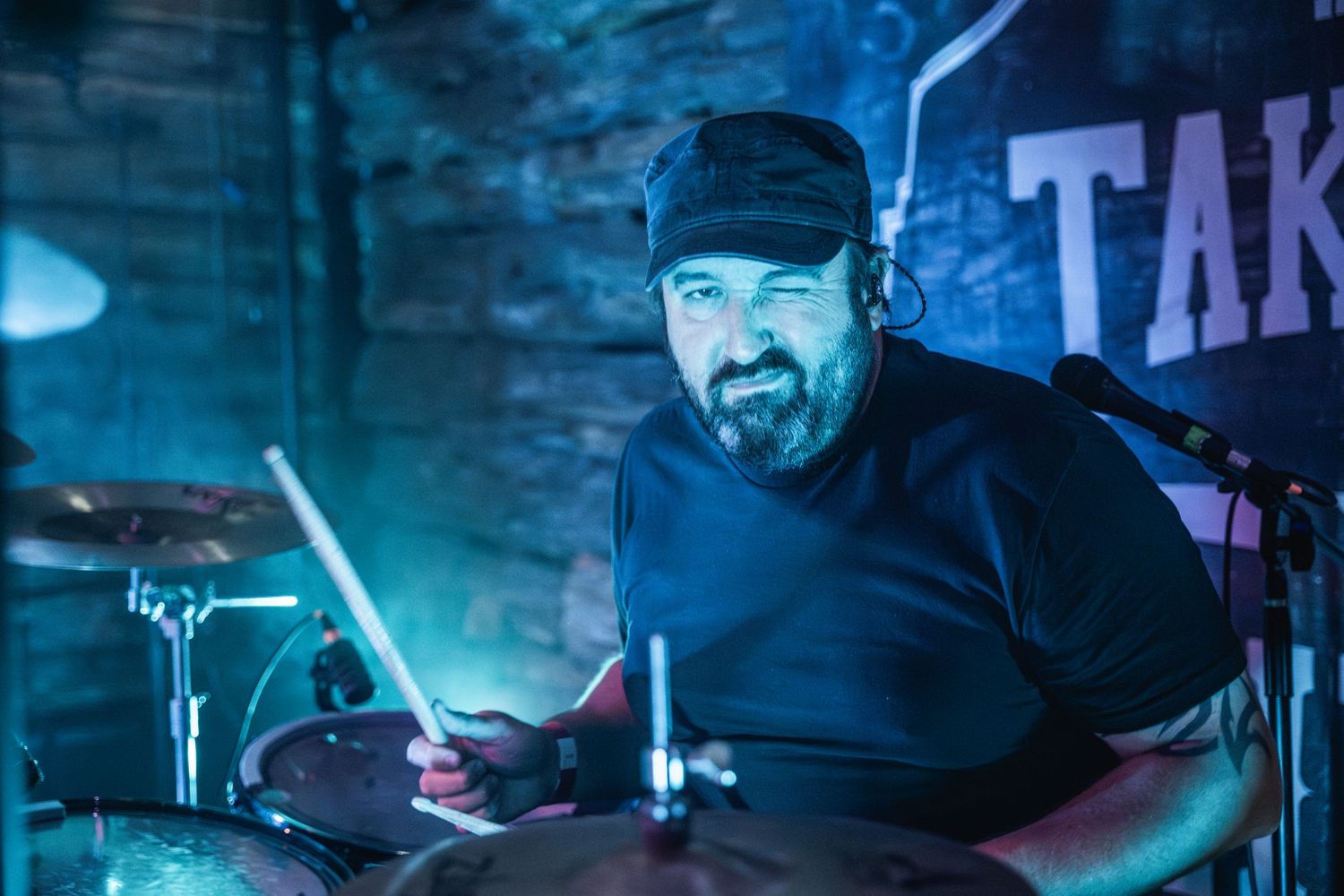Drummer performing in moody blue lighting on stage.